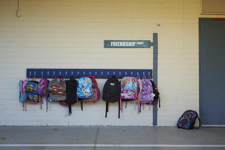 Several childrens backpacks hanging on the wall