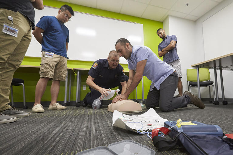 man doing compressions on CPR mannequin