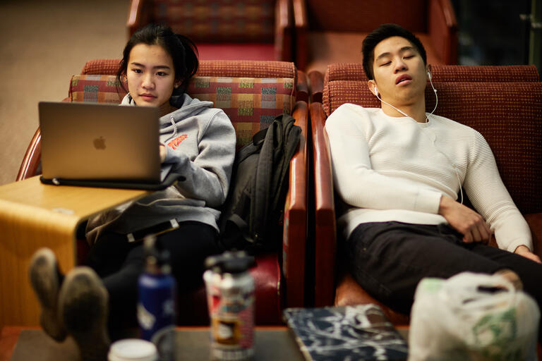 woman with laptop next to sleeping man