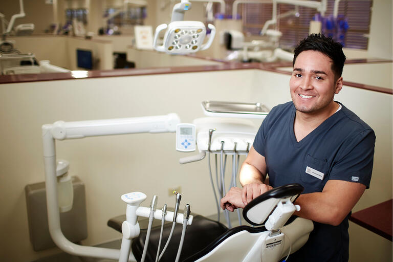 Allesandro Retis leaning on dental examine chair at UNLV School of Dental Medicine.