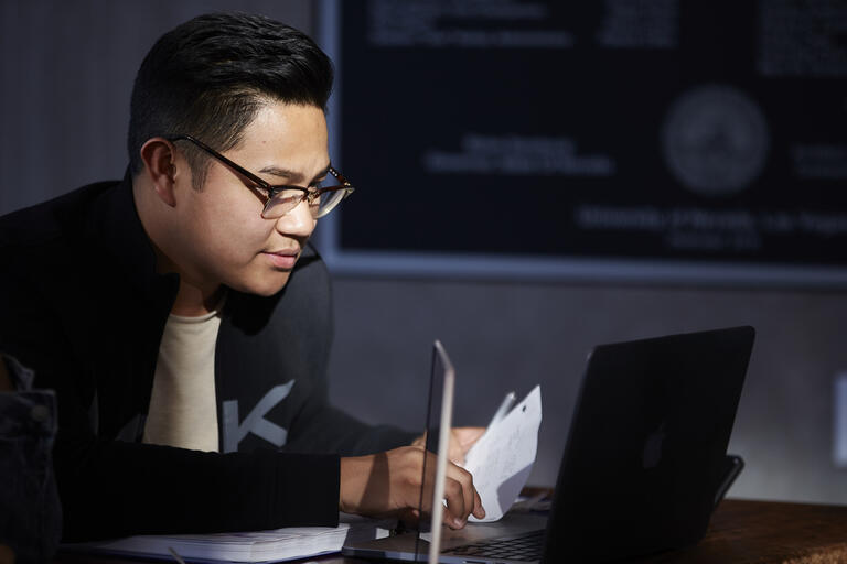A student is bathed in light from his laptop.