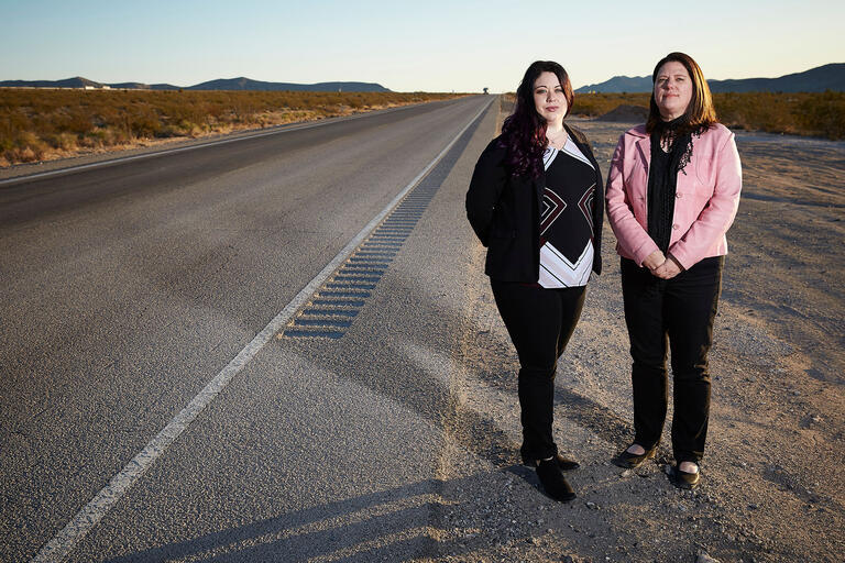two women standing next to empty road