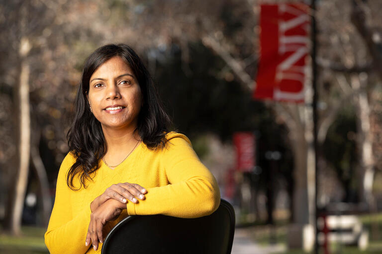 Soumya Upadhyay, poses in front of UNLV banners on campus.