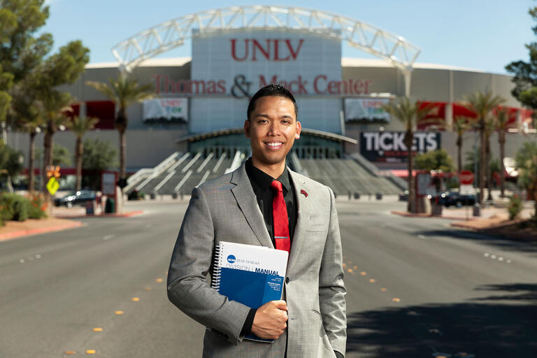 Eric Nepomuceno standing, with book in hand, in front of the Thomas &amp; Mack