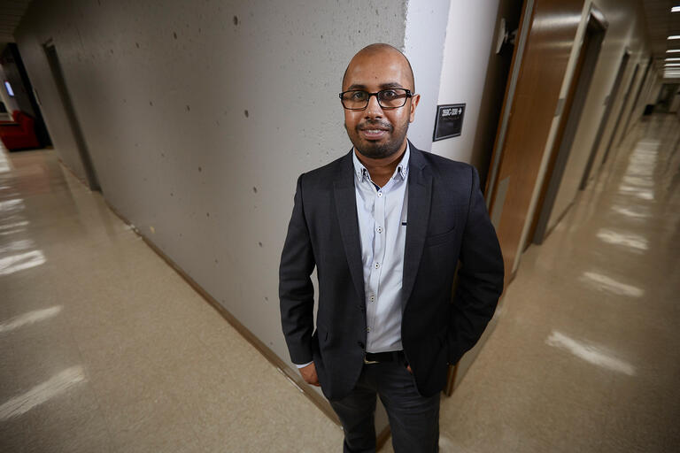 Harsha Perera, Ph.D. Assistant Professor Educational Psychology and Higher Education poses in a hallway.