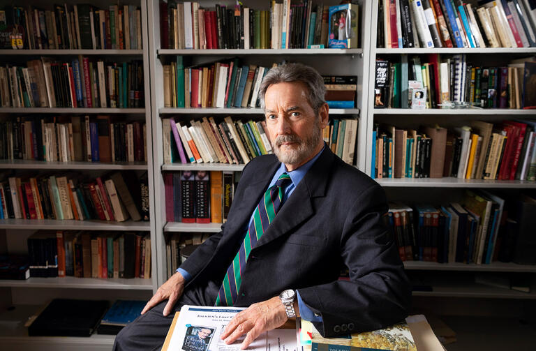 John Bowers poses in front of a bookshelf.