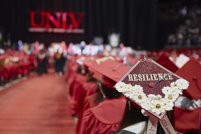 Graduates seated in red caps and gown during a previous UNLV commencement