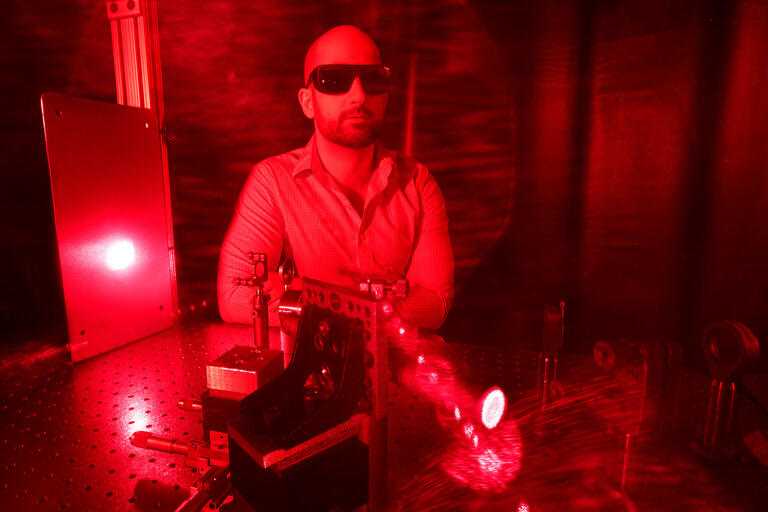 Portrait of Physics and astronomy professor Ashkan Salamat in red light.