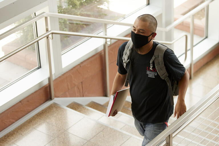 student wearing mask walking up stairs