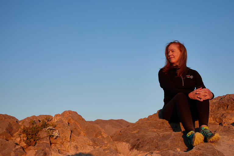 Tina Elkins sitting on a rock looking at the rising sun.