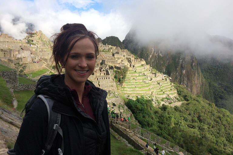 A woman stands in front of Machu Picchu