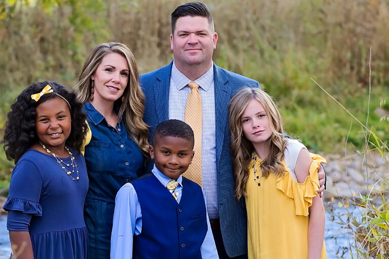 A man stands with his wife, son, and two daughters