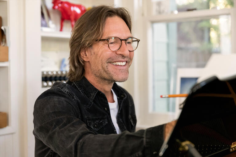 A man smiles while writing music