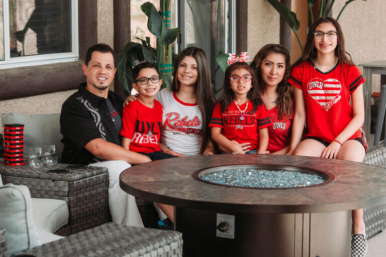 A man sits on a couch with his wife and four children