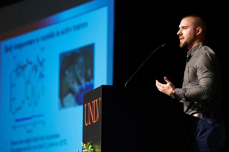 A man stands at a podium in a darkened room
