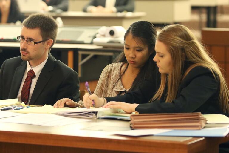 Three students pore over notes at a mock trial.