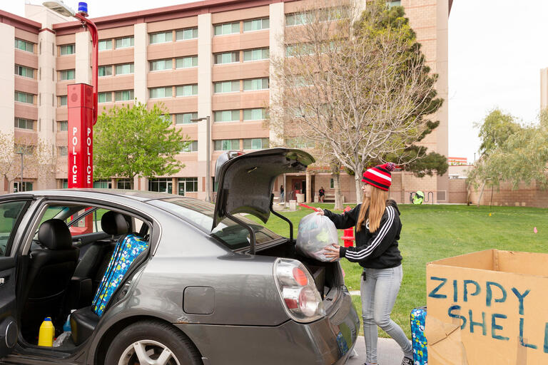 A student loads belongings into the back of her car