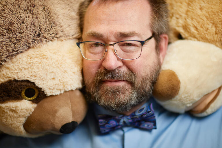 A close up of a man surrounded by stuffed animals