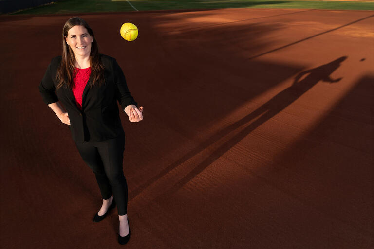 woman in suit tossing softball