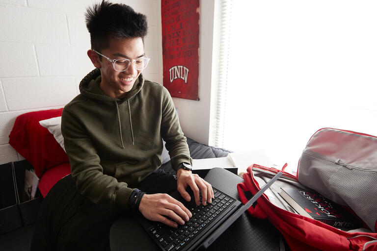 A student works on a laptop in his dorm room
