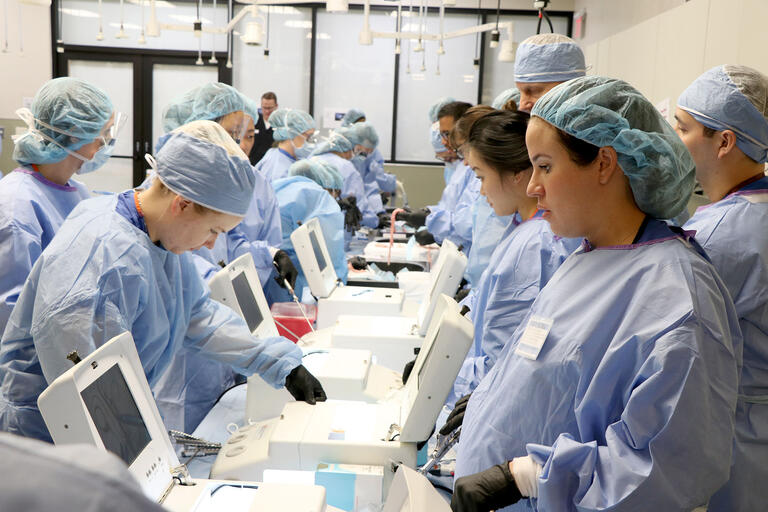 medical students in surgery gowns around equipment