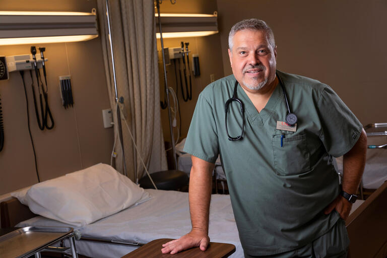 A doctor leans on a table at a hospital bed