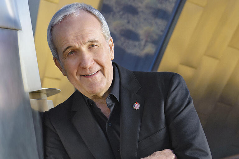 A man leands against a wall with his arms folded