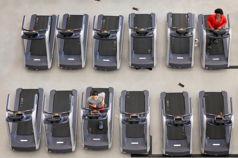 Two students, seen from above, use treadmills far apart