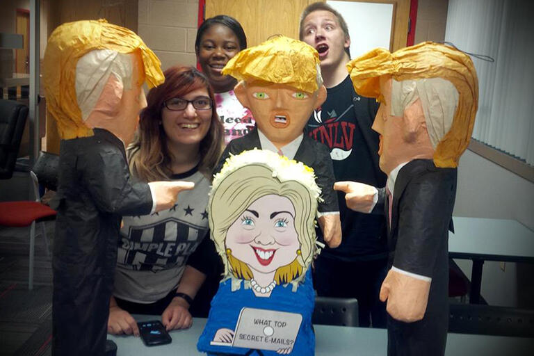 Students pose with Donald Trump and Hillary Clinton piñatas.