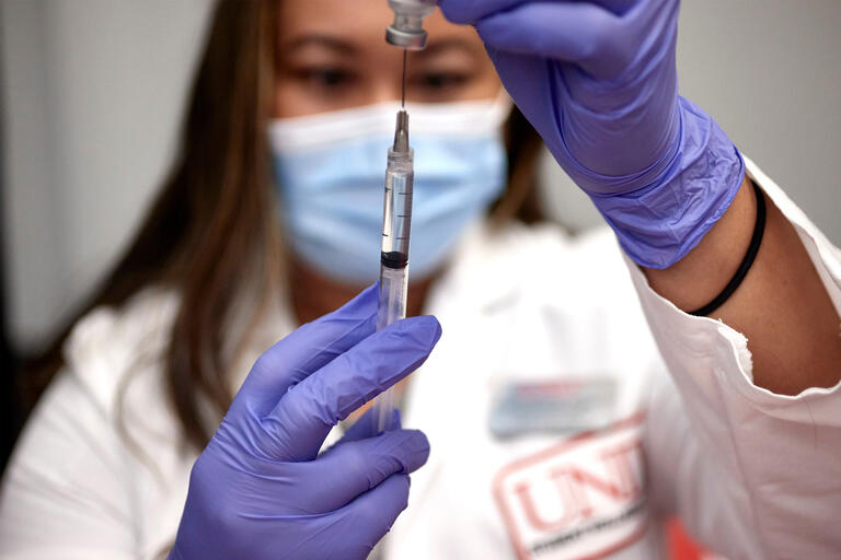A woman prepares a syringe with COVID-19 vaccine