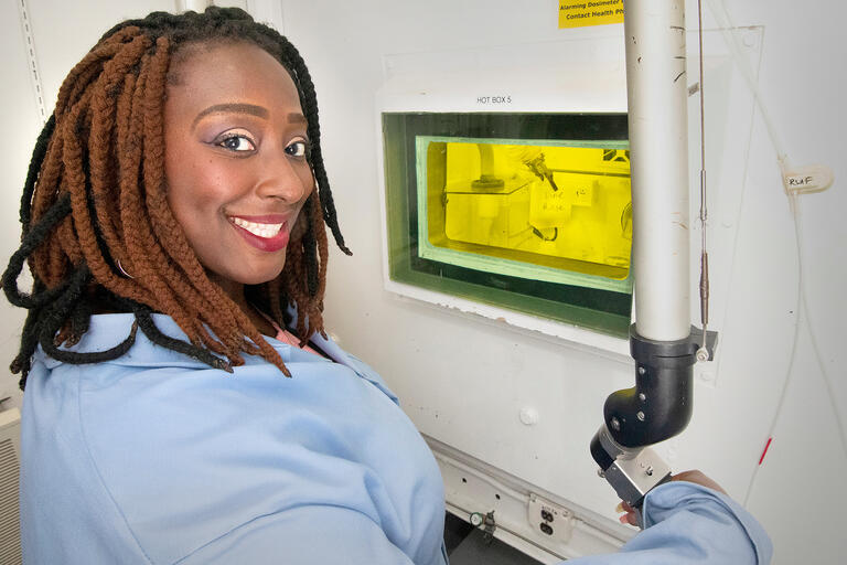 A woman smiles while working with scientific equipment