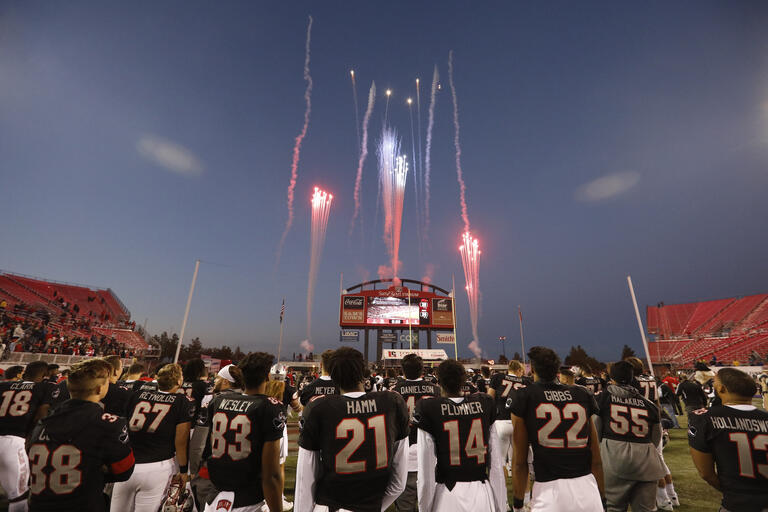 football players look up at fireworks display