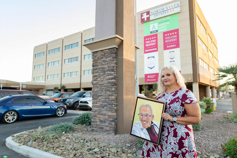 A woman holds a portrait outside a hospital