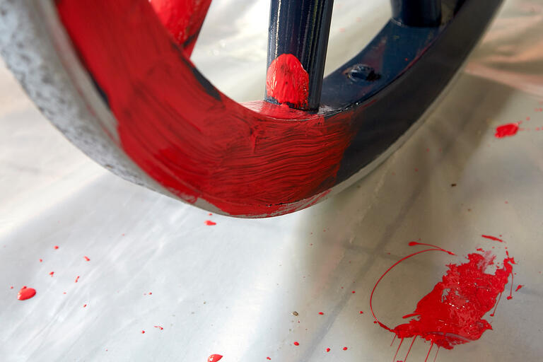 A  blue cannon wheel being painted red.