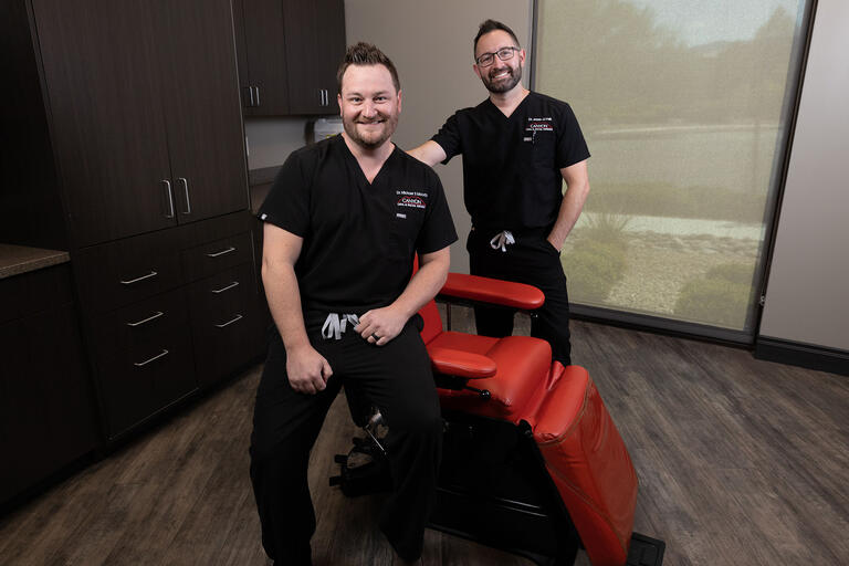 two doctors in scrubs around dental chair