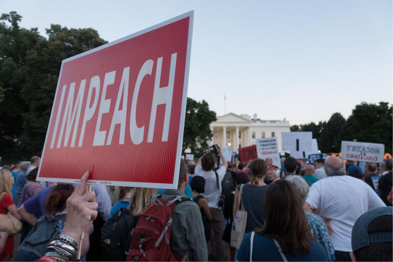 protesters in front of white house holding "impeach" sign