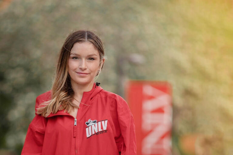 A student wearing a red jacket smiles at the camera