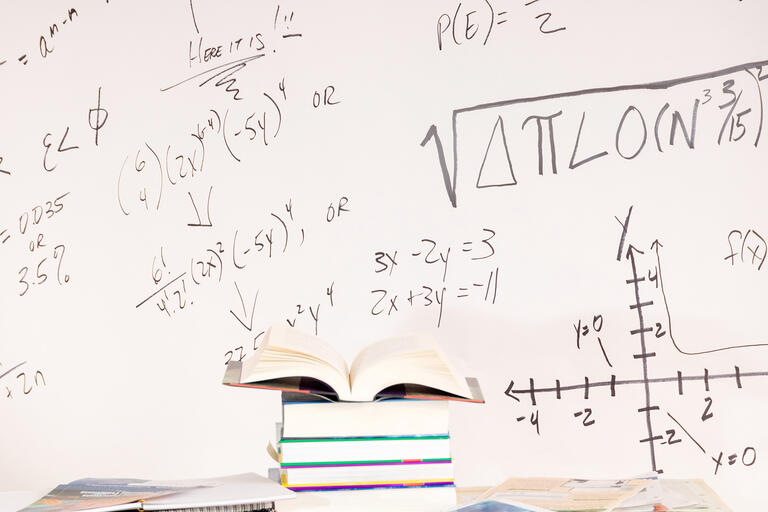 white board with math equations and books