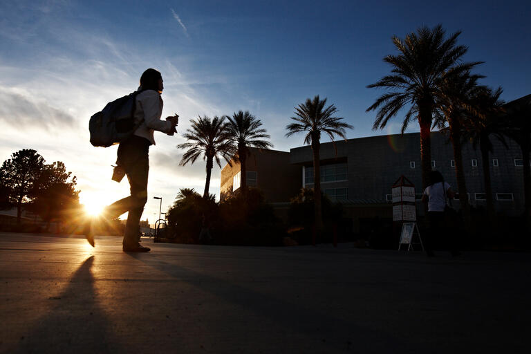 silhouette of student walking on campus during sunset