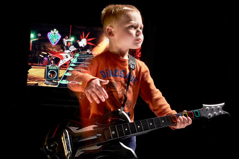 child plays guitar hero guitar