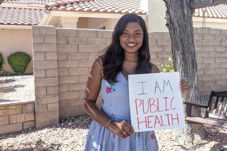 A student holds a sign saying "I Am Public Health"