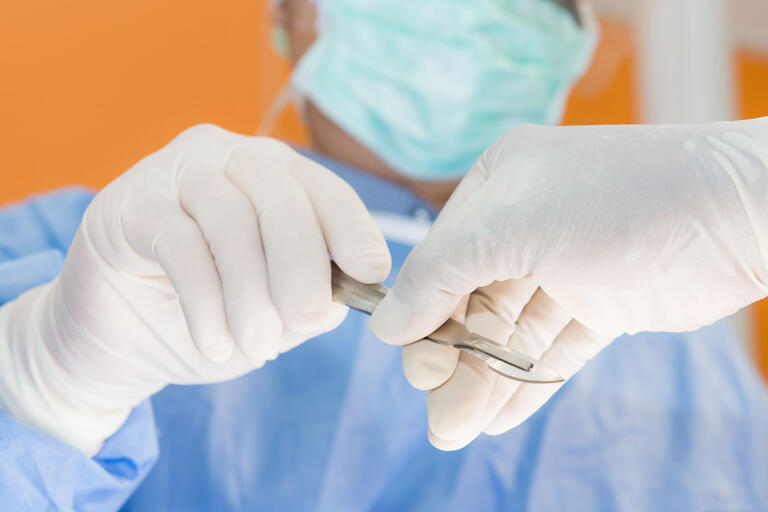gloved hands with scalpel