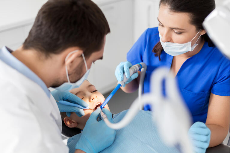 Two dentists cleaning a patient's mouth