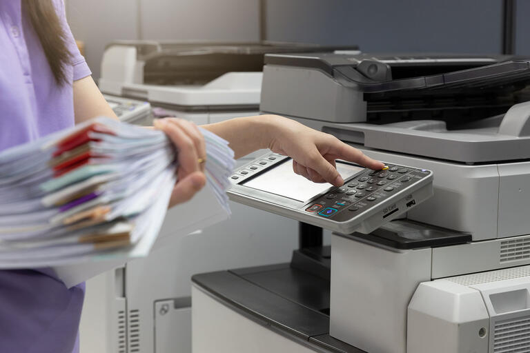 woman at copier with stack of papers