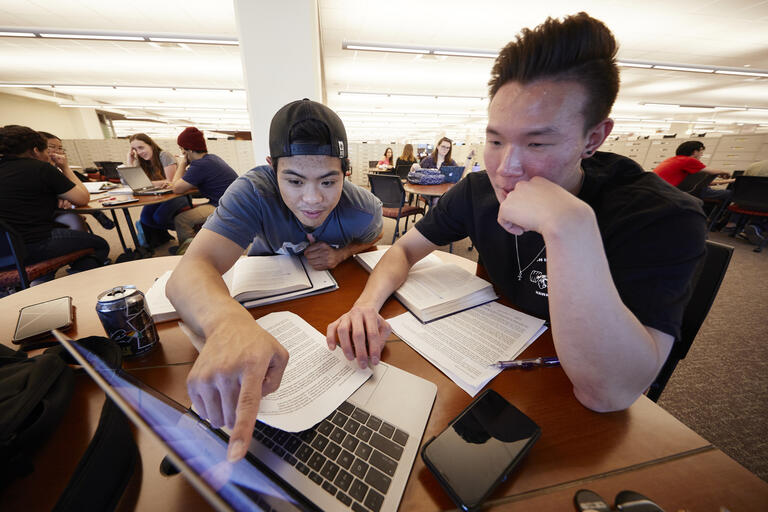 two students working in front of laptop