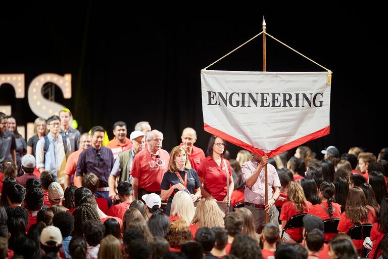 College of Engineering sign being held during a procession at a student event.