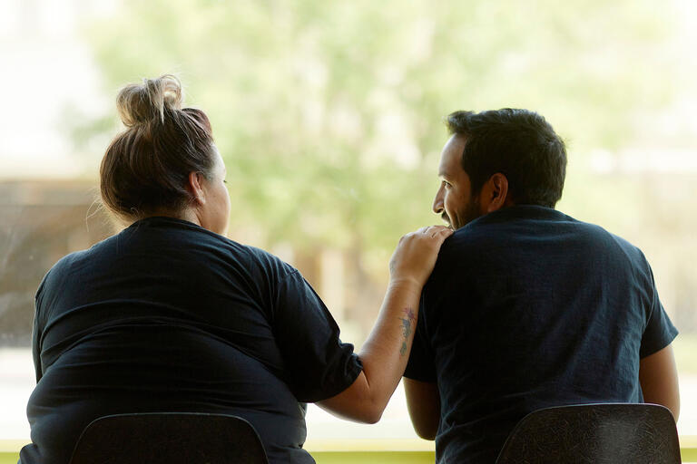 Two people sitting at a table comforting each other