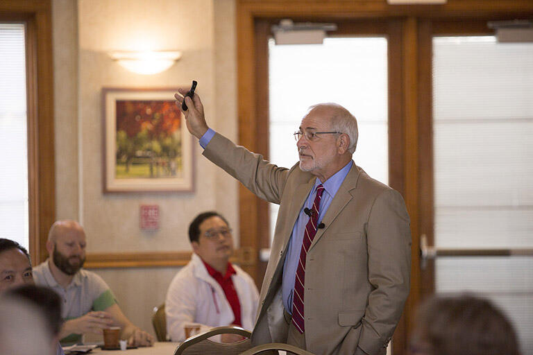 Man in suit raising hand in front of audience.