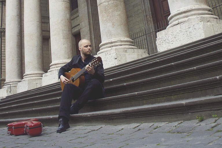man sitting on steps with guitar