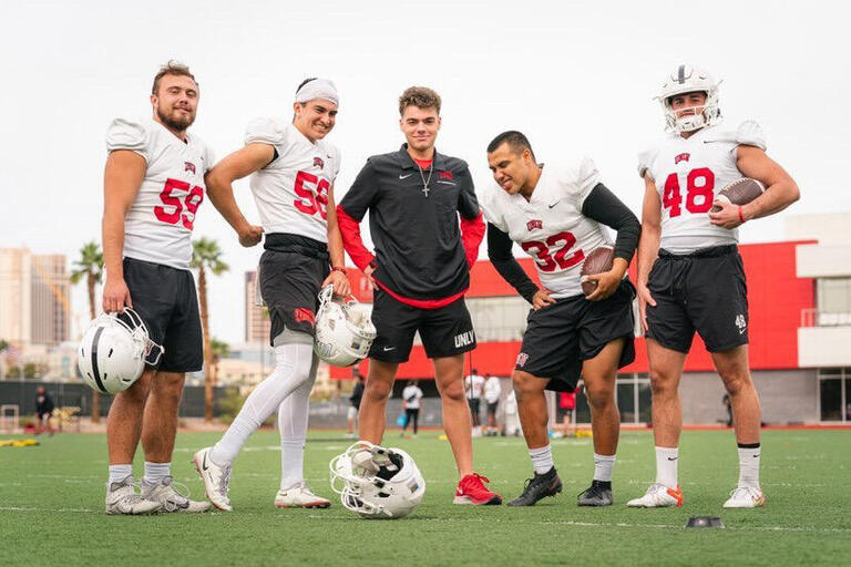 Alex Chackel poses with Rebel football players.